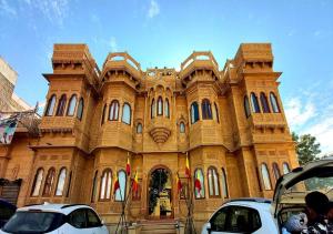 un grande edificio con macchine parcheggiate di fronte di Hotel Lal Garh Fort And Palace a Jaisalmer