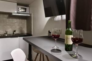 Una botella de vino y dos vasos en una barra de cocina en Halte Mignonne en Houldizy