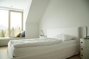 a white bedroom with a bed and a window at Exclusive Alpenlodge ski in ski out Galsterberg in Pruggern