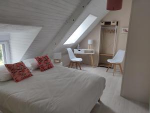 a bedroom with a white bed with two white chairs at Les fleurs du Mont in Céaux