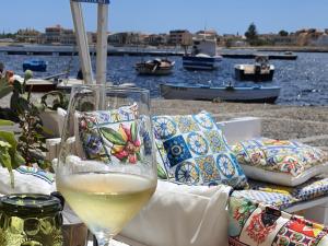 a glass of wine sitting on a table near the water at Amareilmare2 in Marzamemi