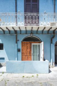 ein blaues Gebäude mit einer Holztür und einem Balkon in der Unterkunft Marina Suite by Wonderful Italy in Palermo