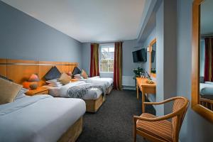 a hotel room with two beds and a desk at Queens Hotel in Ennis