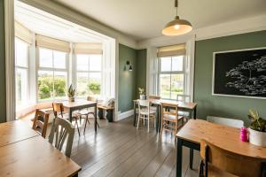 a restaurant with wooden tables and chairs and windows at The Old Vicarage in Cardigan