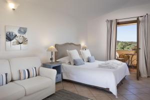 a bedroom with a white bed and a couch at Relais Fenicottero Rosa in Porto San Paolo