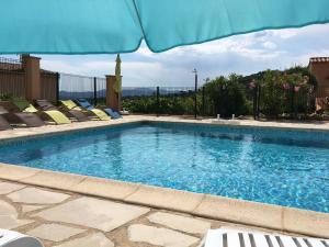 una gran piscina con sillas y sombrilla en Les Oliviers, en Grimaud