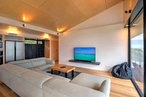 a living room with a couch and a flat screen tv at Atelier in Coles Bay