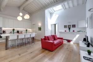 a living room with a red couch and a kitchen at Margot Apartment by Mamo Florence in Florence