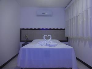 Un dormitorio con una cama blanca con un corazón. en Marlymar Apart Pousada, en Natal