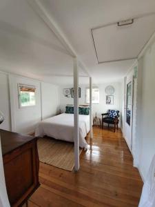 1 dormitorio con cama blanca y suelo de madera en Quinta do Benjamim - Tejo "Experience for 2, family or relax", en Praia do Ribatejo