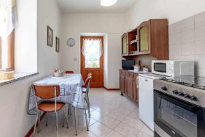 cocina con mesa con sillas y microondas en Casa alle Rose Tenna OSPITAR, en Tenna 