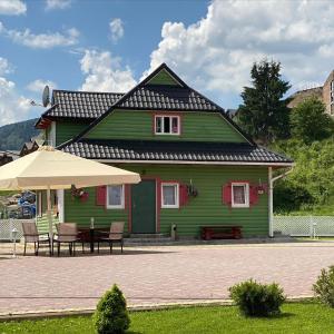 a green house with a table and an umbrella at SKI Xata in Bukovel