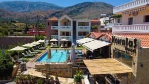 a hotel with a swimming pool and mountains in the background at Kokalas Resort in Georgioupolis