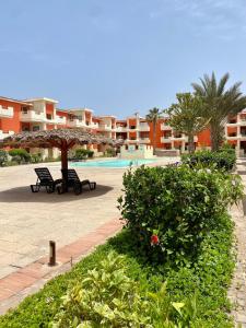 um resort com dois bancos e um guarda-sol e uma piscina em Pool & Wifi - Djadsal Moradias by Bobbywashere em Santa Maria