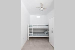 Habitación blanca con ventilador de techo y armario. en Horizonte Atlántico: Un Rincón en el Paraíso en Azano