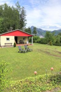 una casa con techo rojo y bancos en un campo en Ferienhaus am Traunsee mit Bergsicht, en Traunkirchen