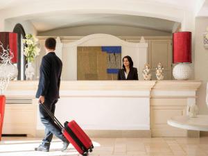 a man with a suitcase walking past a woman at Borgobianco Resort & Spa Polignano - MGallery Collection in Polignano a Mare