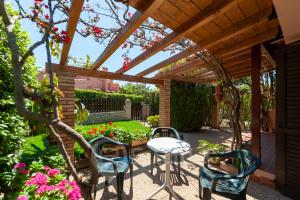 een patio met een tafel en stoelen onder een houten pergola bij Villa Katia - Near the Beach in Simius