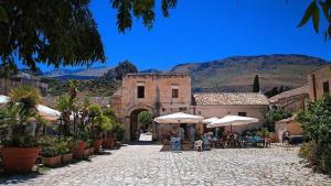 un vecchio edificio con tavoli e ombrelloni in un cortile di Casa vacanza Corallo a Castellammare del Golfo