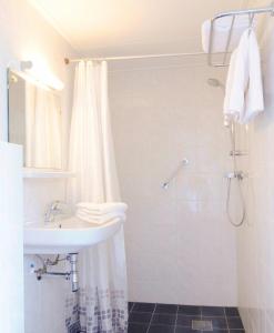 a white bathroom with a shower and a sink at Hotel de Burg in Domburg