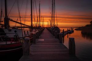 a dock with boats in the water at sunset at Bed & Breakfast De Schans in Makkum