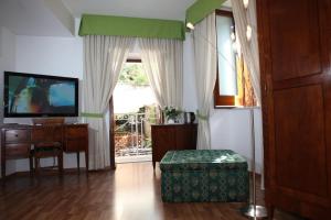 uma sala de estar com uma televisão, uma cadeira e uma mesa em La Magnolia Sorrento - City Centre Hotel em Sorrento