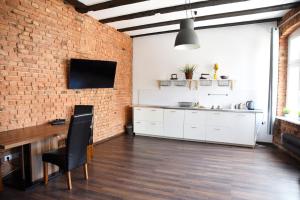 a kitchen with white cabinets and a brick wall at Perfect Stay - "Apartamenty Horzyca" in Toruń