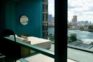 a balcony with a couch and a view of the water at Capella Bangkok in Bangkok