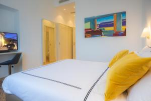 a bedroom with a white bed with a yellow pillow at Leopoldo Rooms in Cagliari