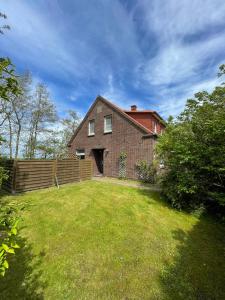 a brick house with a fence and a yard at Bluhm EG in Wangerland