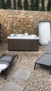 a hot tub and two chairs in front of a stone wall at Apartment BENI in Novi Vinodolski