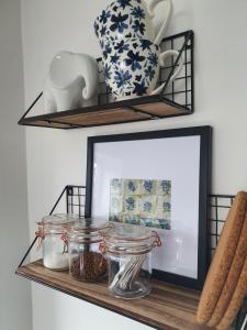 a mirror on a shelf with jars and vases at Cosy Cottage in heart of Llangollen in Llangollen