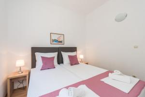 a bedroom with a large white bed with pink pillows at Villa Mihaela in Trogir