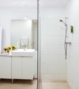 ein weißes Bad mit einem Waschbecken und einer Dusche in der Unterkunft Glück am See - Apartment mit Seezugang in Hallstatt