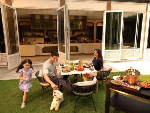 a family sitting around a table with a dog at Capella Bangkok in Bangkok