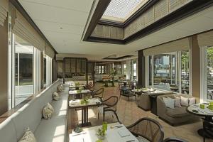 a restaurant with tables and couches and windows at Capella Bangkok in Bangkok