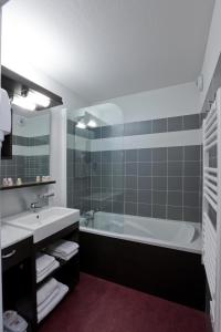 a bathroom with a tub and a sink at Noemys Terrasses de Labrau in La Foux