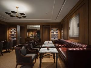 a restaurant with a leather couch and chairs and tables at Capella Bangkok in Bangkok