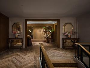 a hallway with two mirrors and two tables with flowers at Capella Bangkok in Bangkok