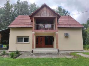 a small house with a wooden door and a balcony at Maci Vendégház in Békéscsaba