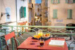 a table with a bowl of fruit and a book on a balcony at Provence Au Coeur Appart Hotels in Forcalquier +64 photos