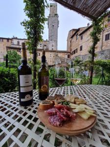 a plate of food on a table with two bottles of wine at Fabio Apartments San Gimignano in San Gimignano