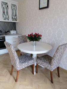 una mesa blanca y sillas con un jarrón de flores en Gandrališkės apartamentai, en Klaipėda