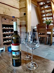 a bottle of wine and two wine glasses on a table at Chata u Horalíků in Humenice