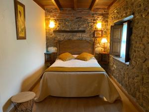 1 dormitorio con 1 cama en una pared de piedra en Hotel Alda, en Avín