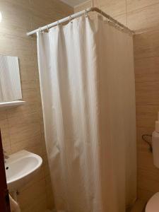 a bathroom with a white shower curtain and a sink at Tapolca Fogadó in Miskolctapolca