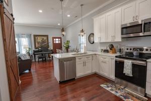 a kitchen with white cabinets and a stove top oven at Remodeled Historic House Walkable to Everything in Raleigh