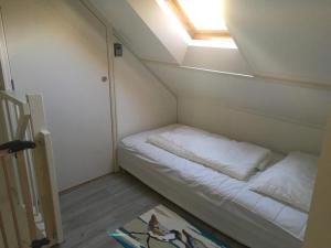 Cette petite chambre comprend un lit et une lucarne. dans l'établissement Heerlijke vakantiehuisjes in Egmond, à Egmond aan Zee