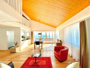 a living room with a red chair and a table at Panorama Boutique Apartment with Air Condition, SPA entry in Solbadhotel in Sigriswil