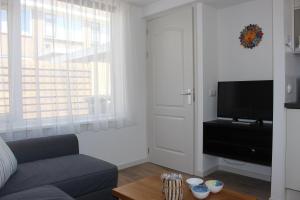 un salon avec un canapé et une télévision dans l'établissement Heerlijke vakantiehuisjes in Egmond, à Egmond aan Zee